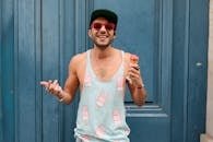 Happy man in Paris enjoying ice cream against a blue door. Fashionable and fun summer vibe.